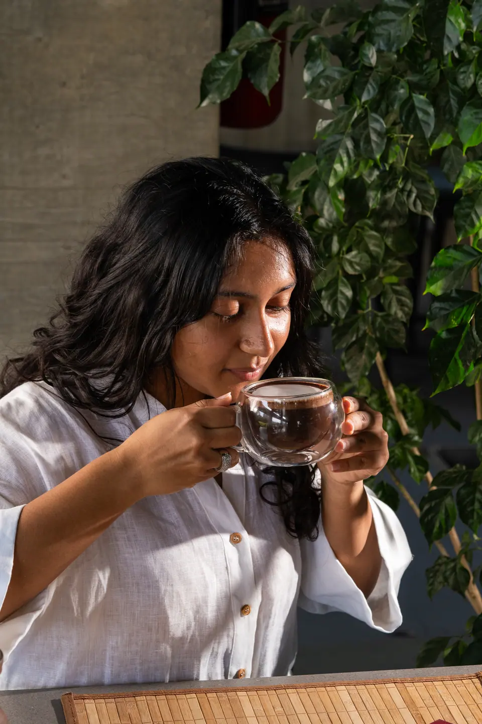 A guest smiling while sipping from a glass cup