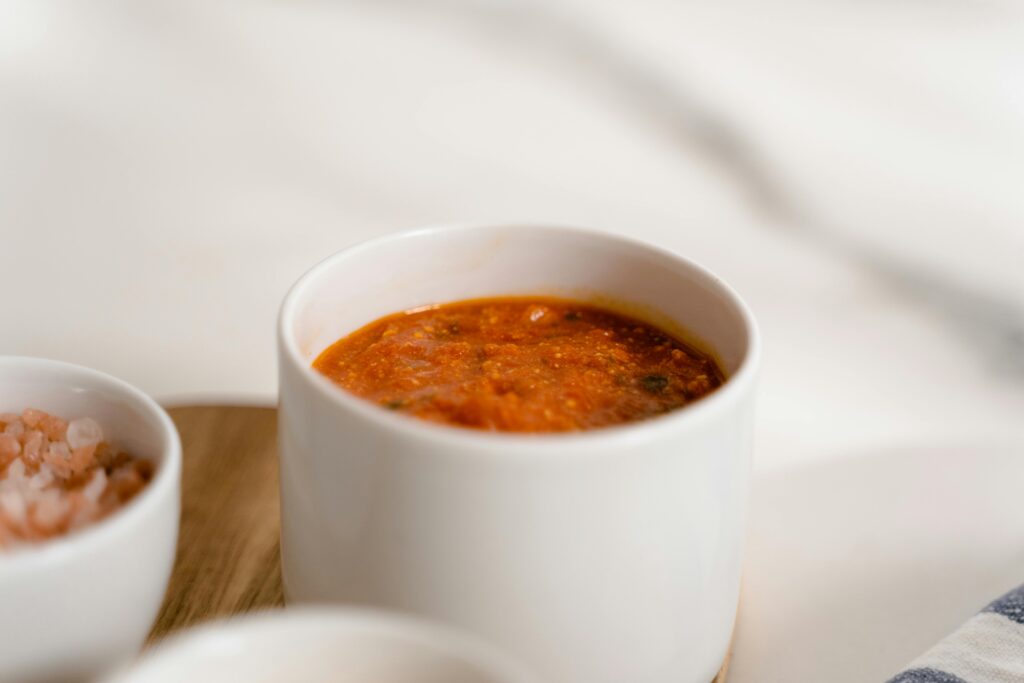 A close-up of rich marinara sauce in a white ceramic cup, perfect for pasta dishes.